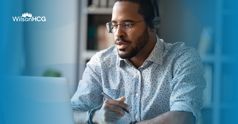 Black man in a button up at a home office on a work call with headphones on