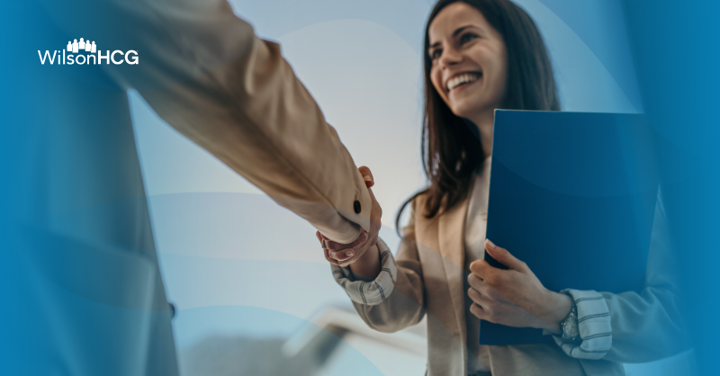 Business woman holding blue folder and shaking hands with someone.