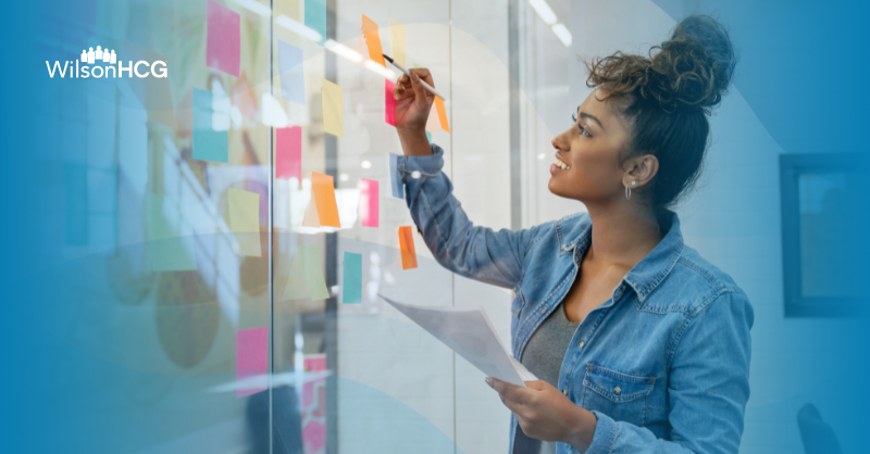 Biracial woman uses colorful sticky notes to brainstorm ideas.