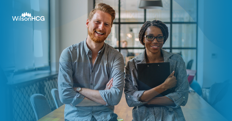 Caucasian male and African American female smiling in modern office.