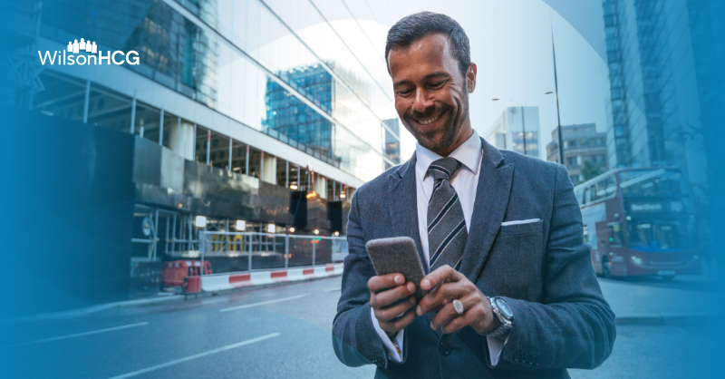 Businessman looks at cellphone while walking in downtown London.