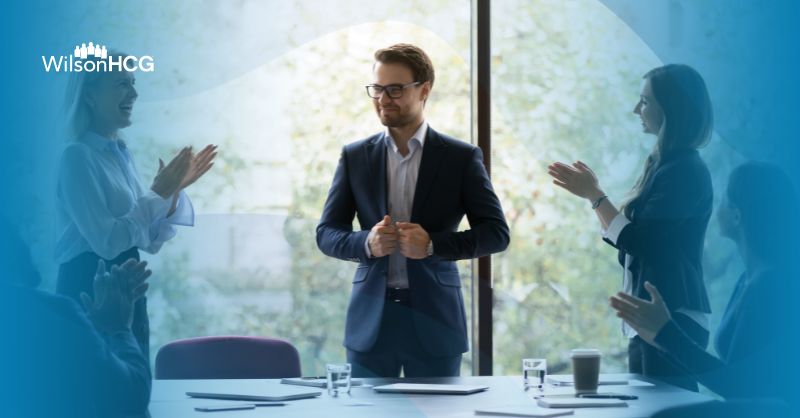 Colleagues clap for CFO who recently won an award.